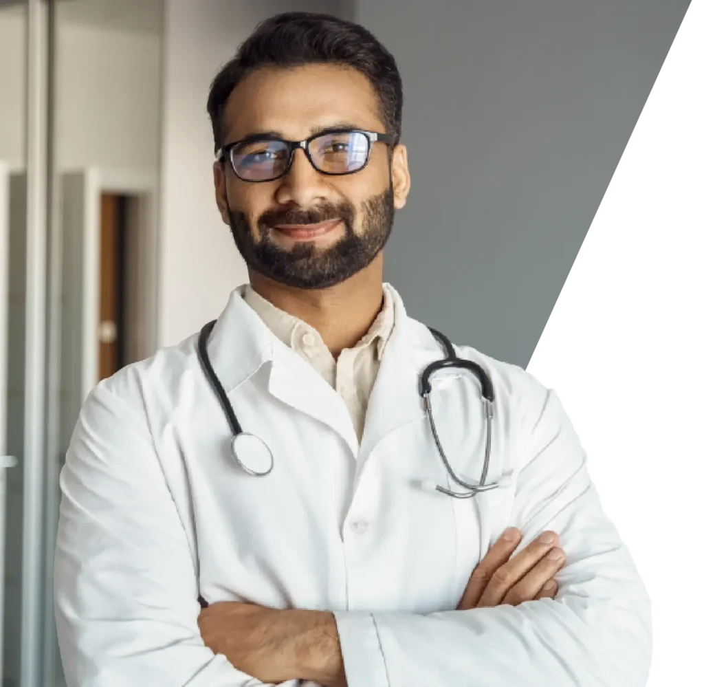 A male physician with glasses and a stethoscope, ready to assist patients in a clinical environment.